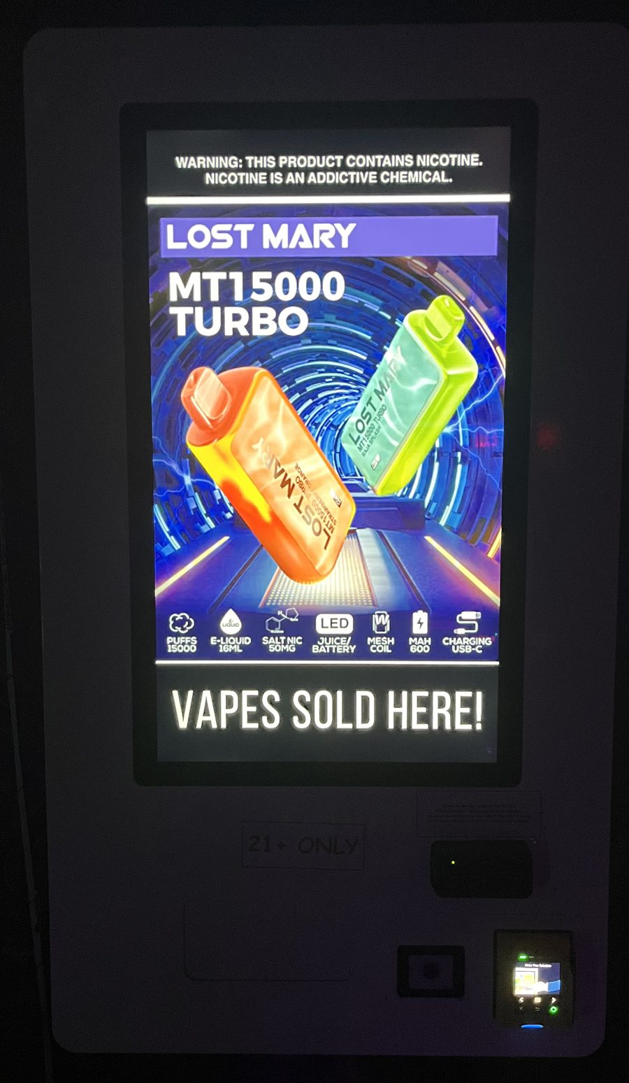 Machine touchscreen showing a product ad, a nicotine warning and Vapes Sold Here, with a 21+ only label below